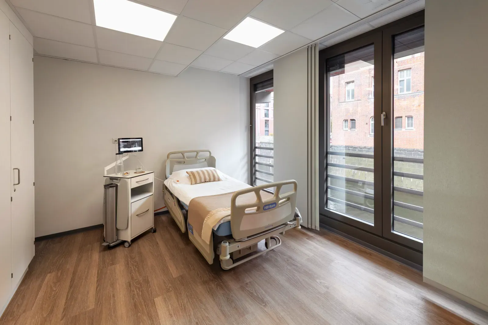 Patient room with nursing bed and view of brick houses