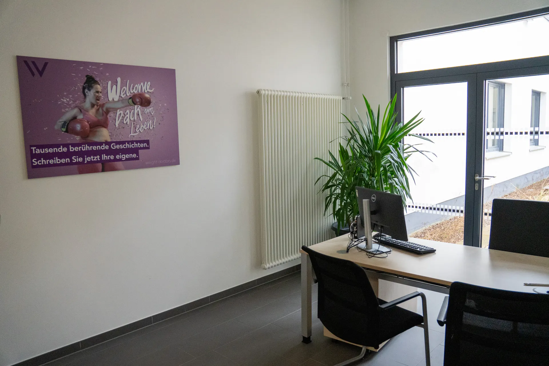 Bright consultation room at the Weight Doctors® Nationalklinik with a desk and a Weight Doctors® poster