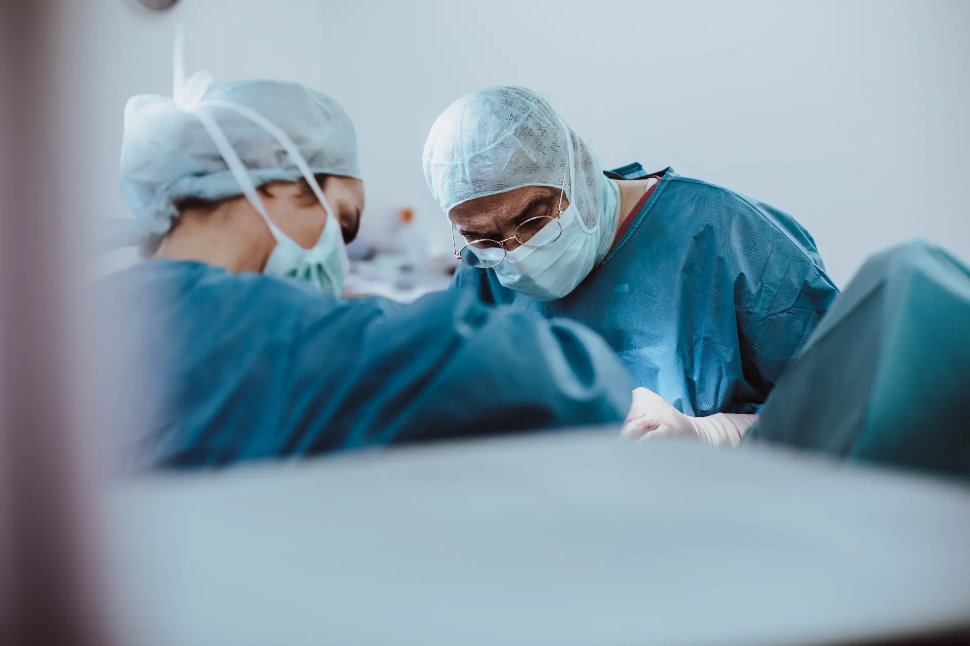 Chirurgin und Chirurg operieren konzentriert am OP-Tisch